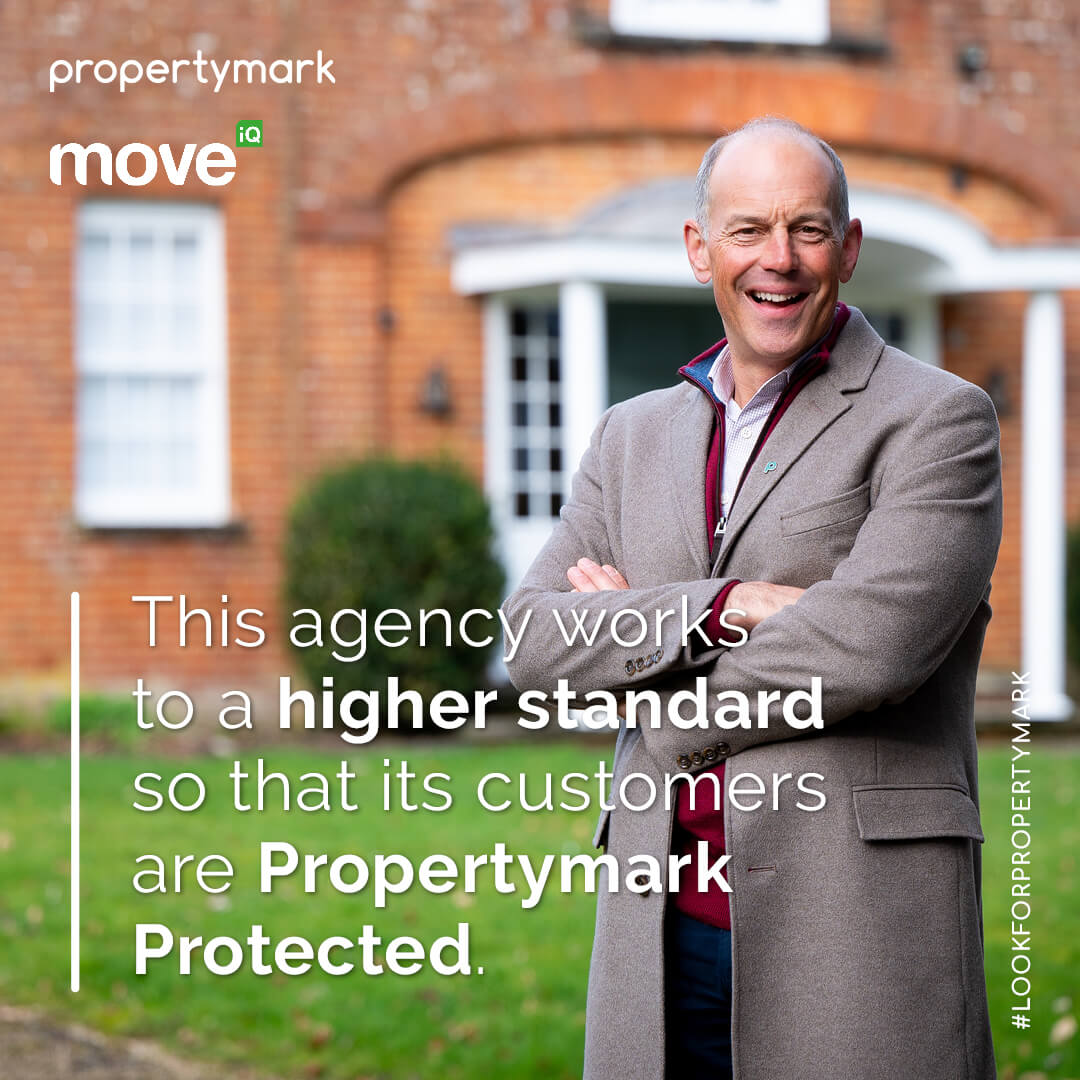 Propertymark - A happy man standing outside a property with his arms crossed.